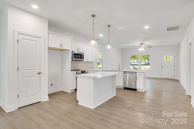 5175 Grand Canyon Rd, Concord, NC 28027 - kitchen with appliances with stainless steel finishes, a peninsula, light wood-style flooring, recessed lighting, and white cabinetry