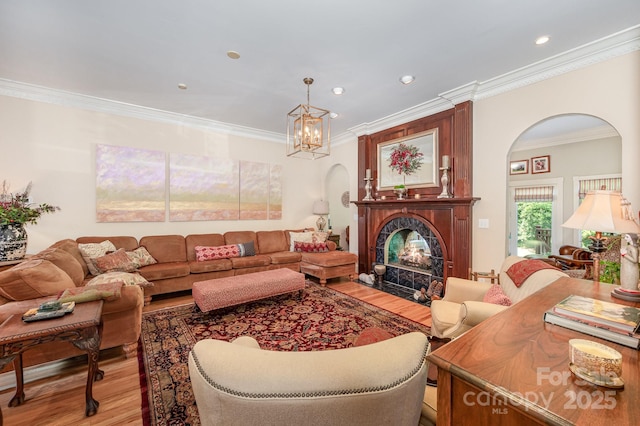 408 Johnsfield Rd, Shelby, NC 28150 - living room featuring light wood-style flooring, ornamental molding, arched walkways, a chandelier, and a warm lit fireplace