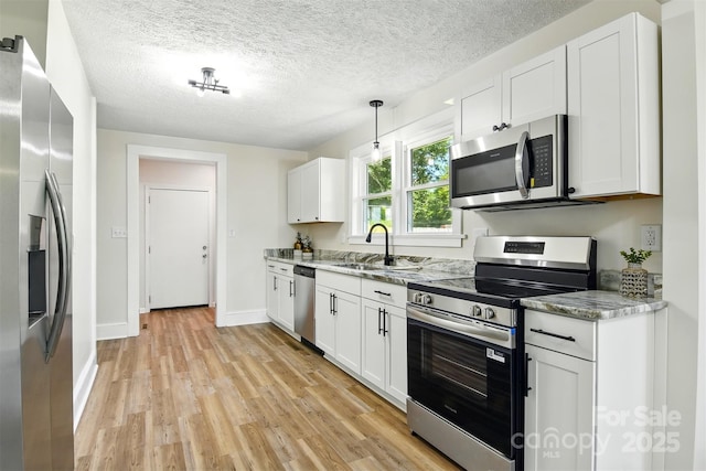 3923 US Highway 321a, Hudson, NC 28638 - kitchen with appliances with stainless steel finishes, light wood finished floors, white cabinets, a sink, and a textured ceiling