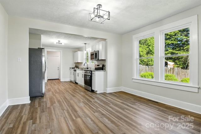 3923 US Highway 321a, Hudson, NC 28638 - kitchen with appliances with stainless steel finishes, a textured ceiling, baseboards, wood finished floors, and white cabinetry