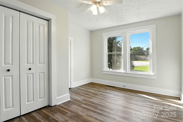 3923 US Highway 321a, Hudson, NC 28638 - unfurnished bedroom with multiple windows, baseboards, dark wood-type flooring, a closet, and a textured ceiling