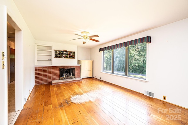 4783 Calico Rd, Lenoir, NC 28645 - unfurnished living room with light wood-style floors, a ceiling fan, a brick fireplace, and built in shelves