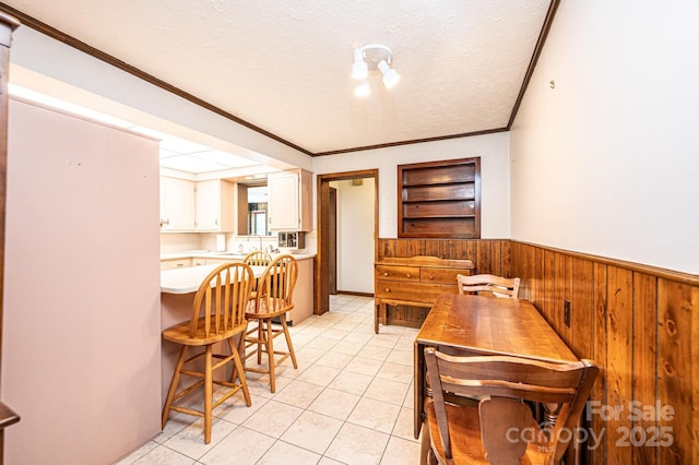 4783 Calico Rd, Lenoir, NC 28645 - dining room featuring wooden walls, a textured ceiling, a wainscoted wall, light tile patterned floors, and crown molding
