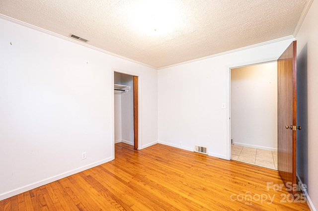 4783 Calico Rd, Lenoir, NC 28645 - unfurnished bedroom featuring a textured ceiling, light wood-style floors, ornamental molding, and a closet