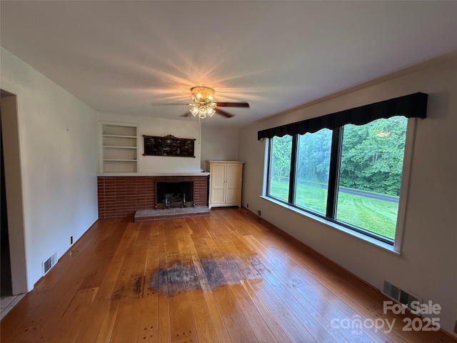 4783 Calico Rd, Lenoir, NC 28645 - unfurnished living room featuring ceiling fan, hardwood / wood-style floors, a fireplace, and built in features