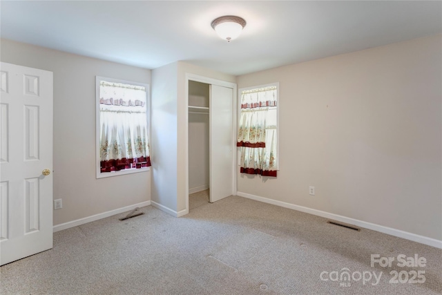 2105 Florida Ave, Kannapolis, NC 28083 - unfurnished bedroom featuring multiple windows, carpet floors, a closet, and baseboards