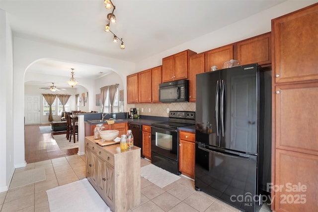1012 Laparc Ln, Indian Trail, NC 28079 - kitchen with black appliances, arched walkways, light tile patterned floors, backsplash, and brown cabinetry