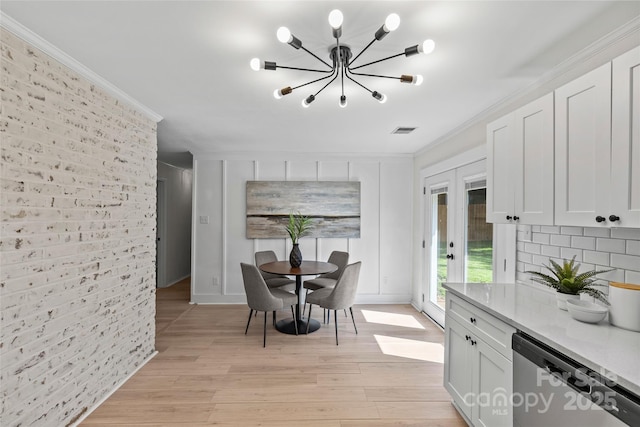 5329 Valley Forge Rd, Charlotte, NC 28210 - dining area featuring a chandelier, brick wall, light wood-style floors, french doors, and crown molding