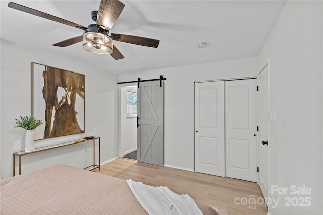 5329 Valley Forge Rd, Charlotte, NC 28210 - bedroom with a barn door, light wood-type flooring, a closet, and a ceiling fan