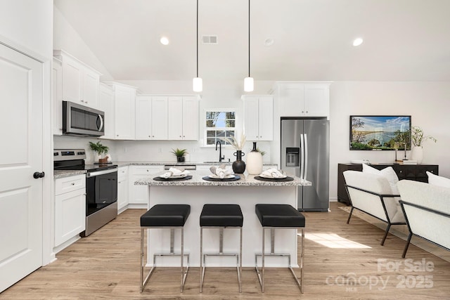 4230 Acorn St, Charlotte, NC 28205 - kitchen with appliances with stainless steel finishes, a breakfast bar, a kitchen island, white cabinetry, and lofted ceiling