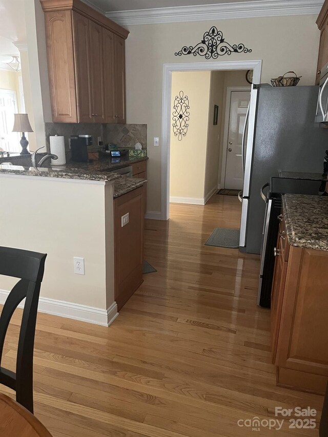 2300 Wednesbury Ct, Kannapolis, NC 28083 - kitchen featuring appliances with stainless steel finishes, ornamental molding, light wood-style floors, dark stone countertops, and tasteful backsplash