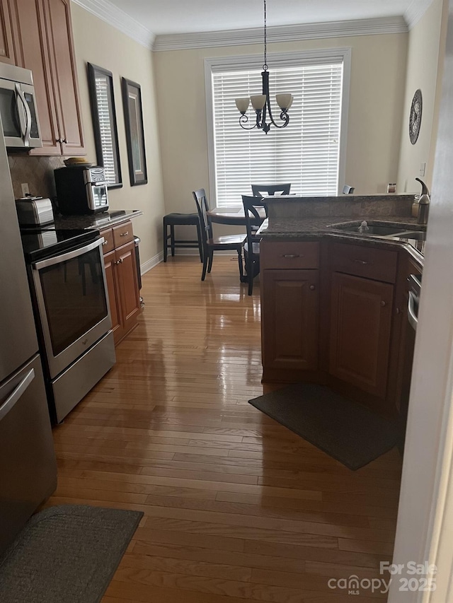 2300 Wednesbury Ct, Kannapolis, NC 28083 - kitchen featuring stainless steel appliances, a chandelier, crown molding, hardwood / wood-style flooring, and dark countertops
