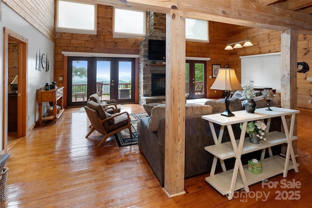 853 Granny Lewis Ln, Mars Hill, NC 28754 - living room featuring a high ceiling, light wood-style flooring, a stone fireplace, wood walls, and french doors