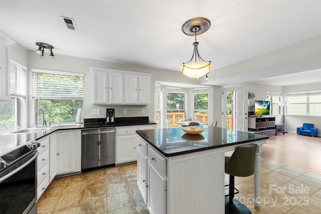 7425 Hubbard Woods Rd, Charlotte, NC 28269 - kitchen featuring appliances with stainless steel finishes, open floor plan, a kitchen bar, and white cabinets