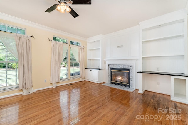1002 Hollyhedge Ln, Indian Trail, NC 28079 - unfurnished living room with a high end fireplace, built in features, a ceiling fan, wood finished floors, and ornamental molding