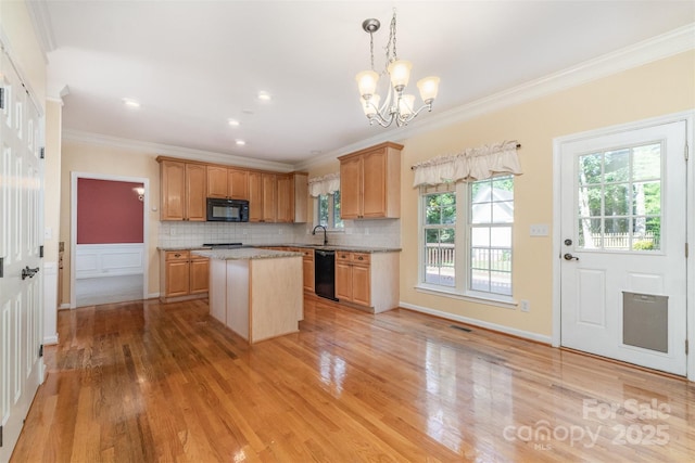 1002 Hollyhedge Ln, Indian Trail, NC 28079 - kitchen with black appliances, ornamental molding, a kitchen island, light wood-type flooring, and a chandelier