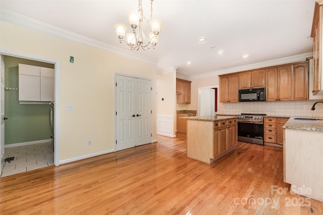 1002 Hollyhedge Ln, Indian Trail, NC 28079 - kitchen featuring black microwave, stainless steel range oven, a center island, ornamental molding, and light stone counters