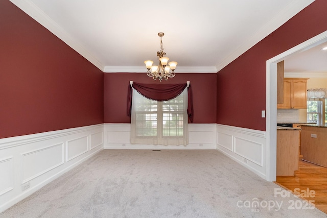 1002 Hollyhedge Ln, Indian Trail, NC 28079 - spare room with crown molding, a chandelier, a decorative wall, wainscoting, and light colored carpet