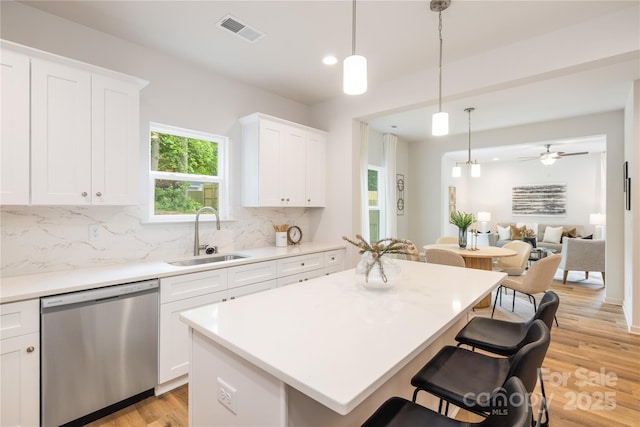 4226 Acorn St, Charlotte, NC 28205 - kitchen with dishwasher, a sink, a breakfast bar area, decorative backsplash, and light wood-style flooring