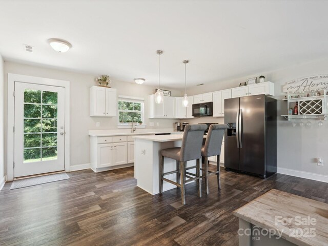 429 Summer Ridge Dr, Stanley, NC 28164 - kitchen with stainless steel fridge with ice dispenser, black microwave, white cabinets, a kitchen breakfast bar, and dark wood-style flooring