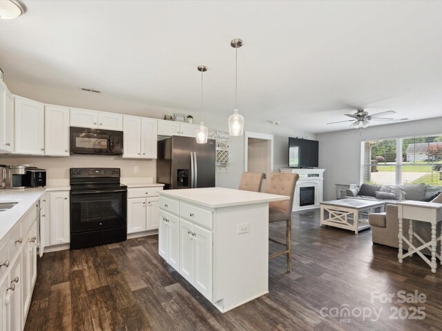 429 Summer Ridge Dr, Stanley, NC 28164 - kitchen with black appliances, a breakfast bar, dark wood finished floors, and white cabinets