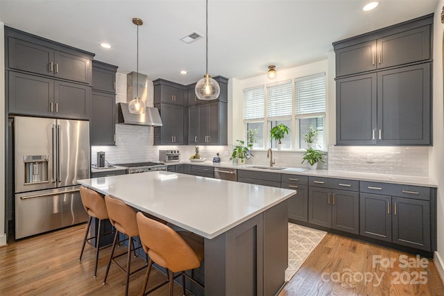 3026 Kalex Ct, Charlotte, NC 28204 - kitchen with stainless steel appliances, wall chimney range hood, light wood-style floors, a kitchen breakfast bar, and decorative backsplash