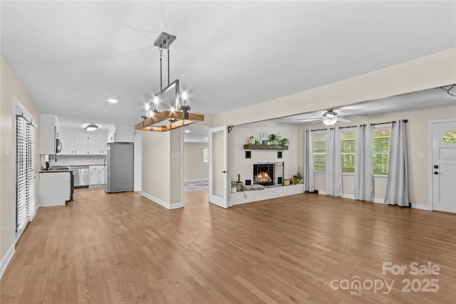 2229 Old Wilkesboro Rd, Statesville, NC 28625 - unfurnished living room with light wood-type flooring, a fireplace, baseboards, and a ceiling fan