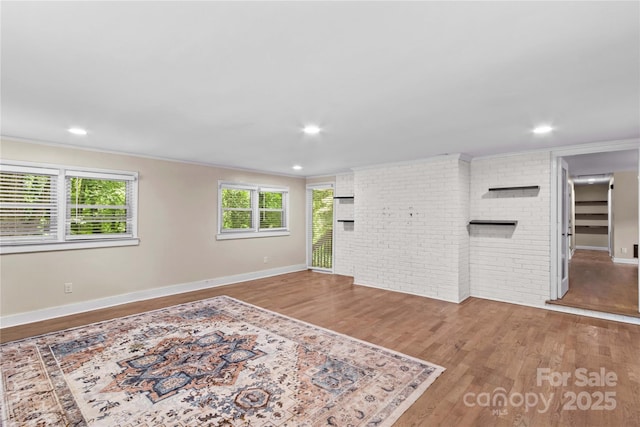 2229 Old Wilkesboro Rd, Statesville, NC 28625 - unfurnished living room with crown molding, wood finished floors, baseboards, recessed lighting, and brick wall