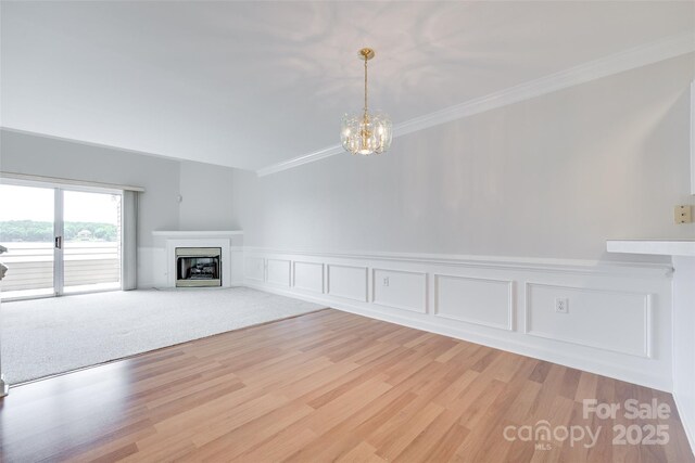 14053 Queens Harbor Rd, Charlotte, NC 28278 - unfurnished living room featuring ornamental molding, a fireplace, a chandelier, a decorative wall, and light wood-type flooring