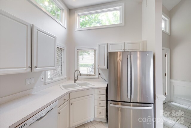 14053 Queens Harbor Rd, Charlotte, NC 28278 - kitchen featuring freestanding refrigerator, white dishwasher, a towering ceiling, white cabinets, and healthy amount of natural light