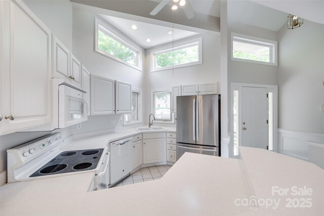 14053 Queens Harbor Rd, Charlotte, NC 28278 - kitchen with white appliances, a towering ceiling, light countertops, healthy amount of natural light, and a ceiling fan