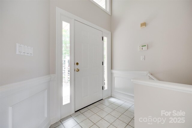 14053 Queens Harbor Rd, Charlotte, NC 28278 - foyer entrance featuring plenty of natural light, light tile patterned floors, a wainscoted wall, and a decorative wall