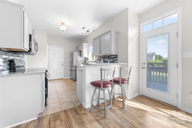 5104 Timbertop Ln, Charlotte, NC 28215 - kitchen with stainless steel appliances, a peninsula, tasteful backsplash, a kitchen breakfast bar, and light wood-style floors