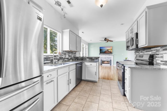 5104 Timbertop Ln, Charlotte, NC 28215 - kitchen featuring stainless steel appliances, ceiling fan, a fireplace, open floor plan, and tasteful backsplash