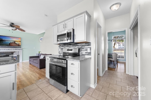 5104 Timbertop Ln, Charlotte, NC 28215 - kitchen featuring appliances with stainless steel finishes, a ceiling fan, light tile patterned floors, open floor plan, and decorative backsplash