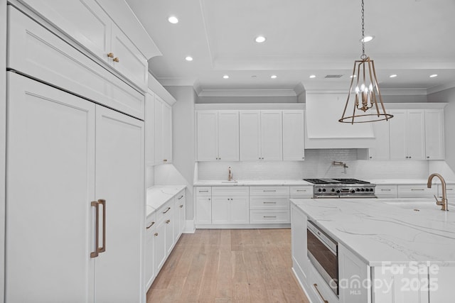 19329 Watermark Dr Unit 422, Cornelius, NC 28031 - kitchen with stainless steel appliances, crown molding, light wood finished floors, white cabinetry, and custom exhaust hood