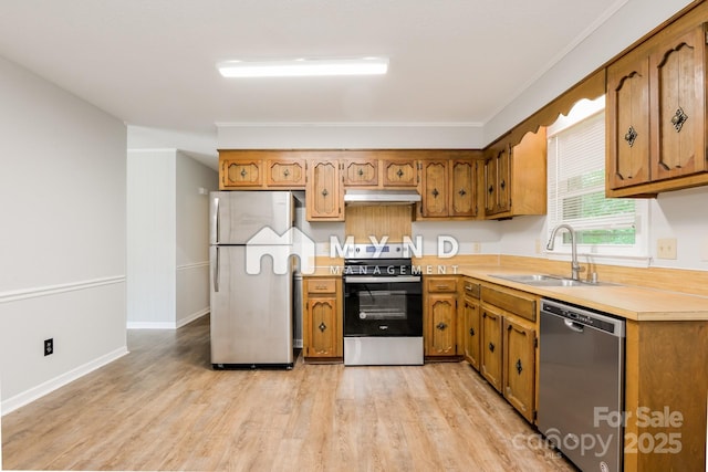 4308 Pinto Ln, Gastonia, NC 28052 - kitchen featuring appliances with stainless steel finishes, under cabinet range hood, light countertops, light wood-type flooring, and brown cabinetry