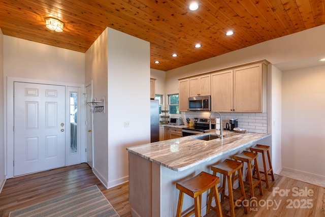 114 Slickrock Rd Unit C/3, Burnsville, NC 28714 - kitchen featuring appliances with stainless steel finishes, a peninsula, light stone counters, a breakfast bar area, and backsplash