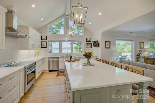 18205 Royal Oak Rd, Charlotte, NC 28278 - kitchen featuring stainless steel appliances, wall chimney range hood, a chandelier, light wood-style flooring, and a center island