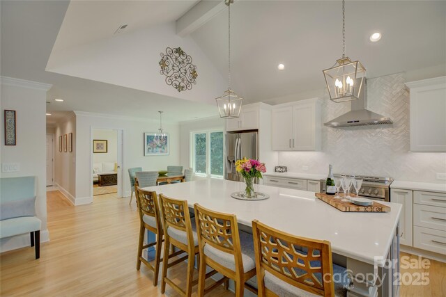 18205 Royal Oak Rd, Charlotte, NC 28278 - kitchen featuring wall chimney range hood, stainless steel appliances, a chandelier, backsplash, and white cabinetry