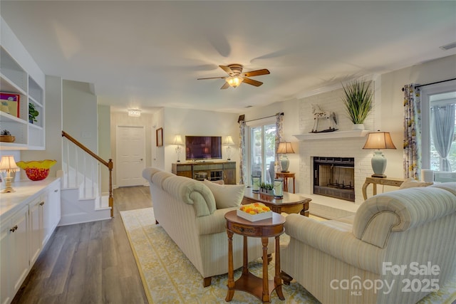 18205 Royal Oak Rd, Charlotte, NC 28278 - living room featuring wood finished floors, a brick fireplace, stairs, and ceiling fan