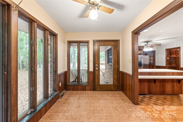 3985 Well Rd, Mint Hill, NC 28227 - foyer entrance with a wainscoted wall, a ceiling fan, wood walls, and a textured ceiling