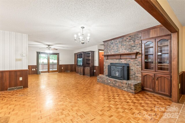 3985 Well Rd, Mint Hill, NC 28227 - unfurnished living room featuring wood walls, a textured ceiling, wainscoting, a chandelier, and ceiling fan