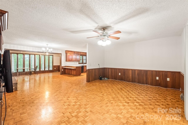 3985 Well Rd, Mint Hill, NC 28227 - empty room featuring a chandelier, ceiling fan, a wainscoted wall, a textured ceiling, and wood walls