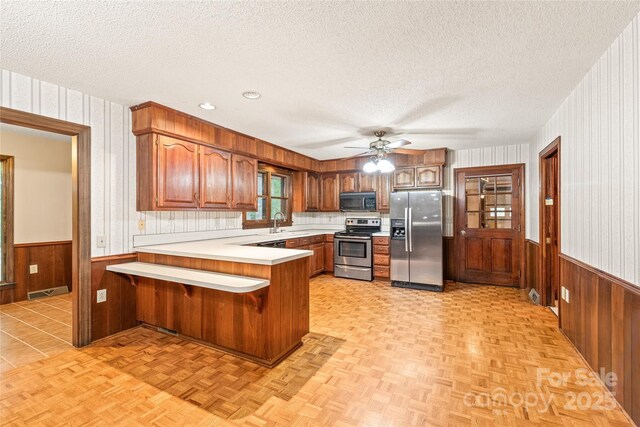 3985 Well Rd, Mint Hill, NC 28227 - kitchen with stainless steel appliances, a textured ceiling, a peninsula, wainscoting, and light countertops