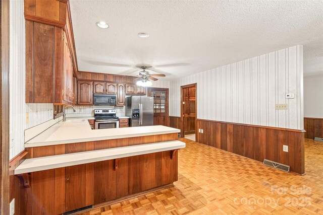 3985 Well Rd, Mint Hill, NC 28227 - kitchen featuring stainless steel appliances, a textured ceiling, a sink, wainscoting, and a ceiling fan