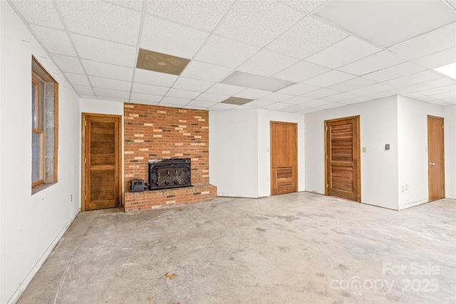 3985 Well Rd, Mint Hill, NC 28227 - unfurnished living room featuring a wood stove, a paneled ceiling, and baseboards