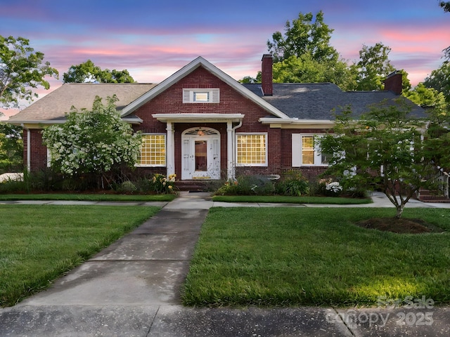 729 Montgomery Ave, Albemarle, NC 28001 - view of front facade with a chimney, brick siding, a lawn, and a shingled roof