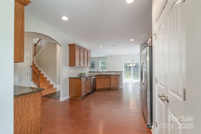 11922 Kimberfield Rd, Matthews, NC 28105 - kitchen featuring appliances with stainless steel finishes, a peninsula, dark wood-type flooring, backsplash, and brown cabinets