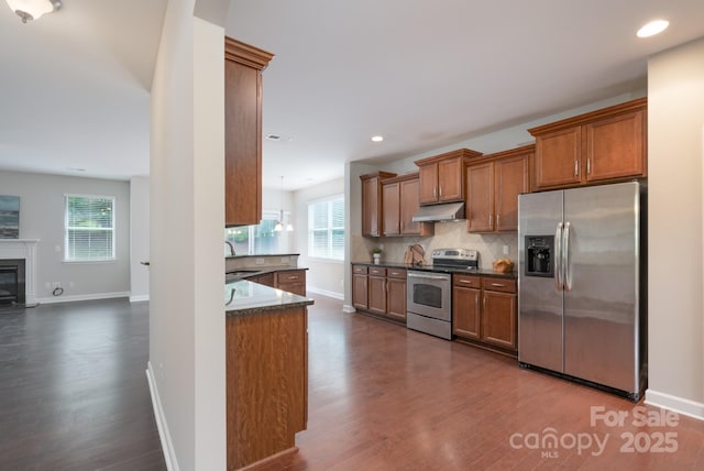 11922 Kimberfield Rd, Matthews, NC 28105 - kitchen with stainless steel appliances, dark countertops, dark wood finished floors, under cabinet range hood, and brown cabinetry